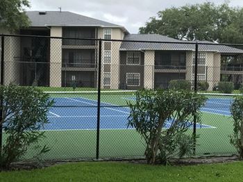 A tennis court in front of an apartment building
